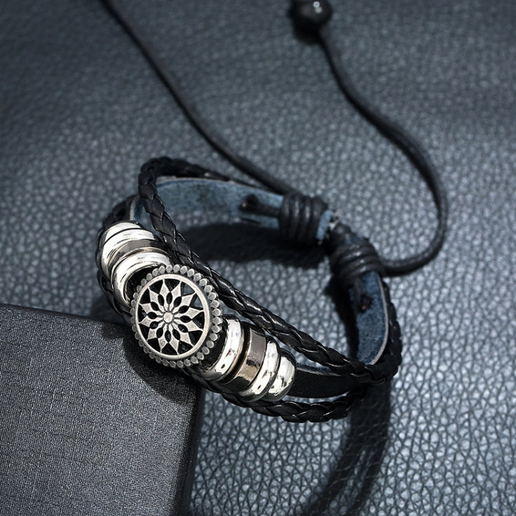 Braided black leather bracelet with circular flower emblem and stacked silver rings