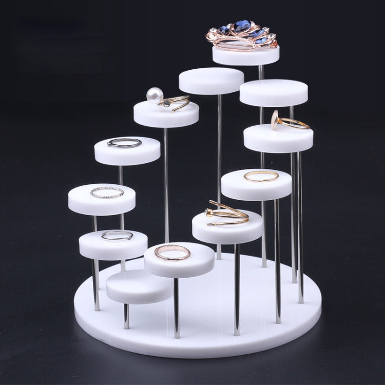 White acrylic ring display stand with round pegs holding assorted rings