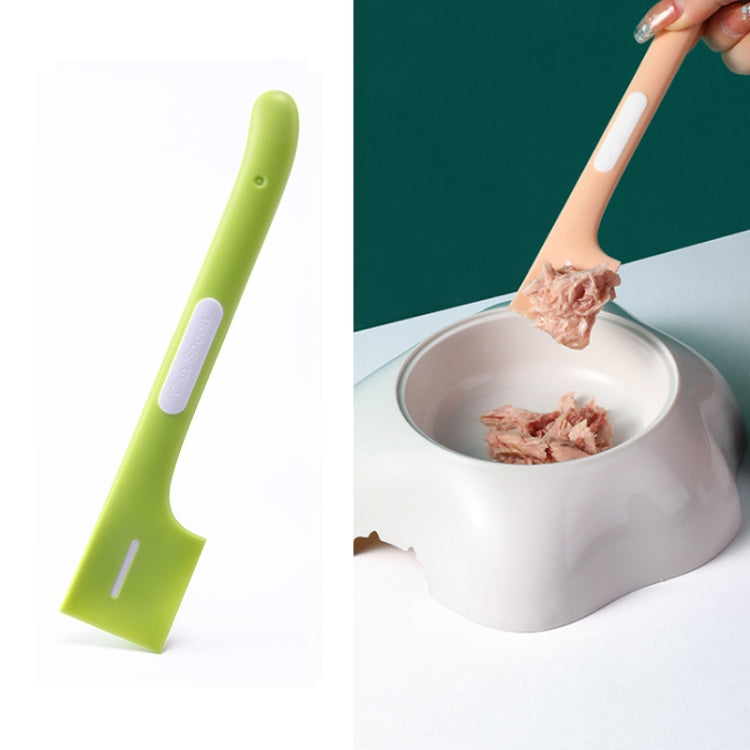 Fruit green long-handled cat-shaped spoon mixing wet pet food in a metal bowl.