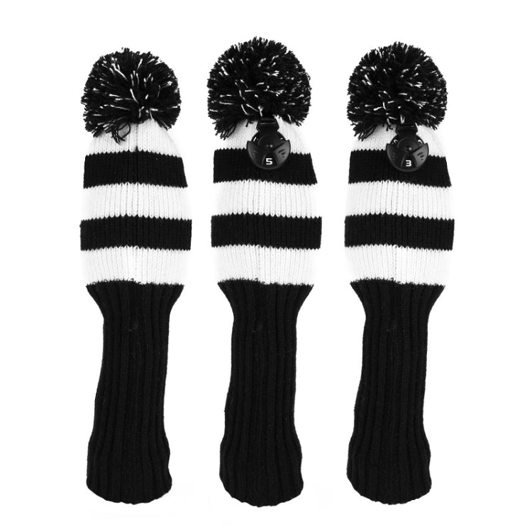 Three black-and-white striped knitted golf club covers with pom-pom tops