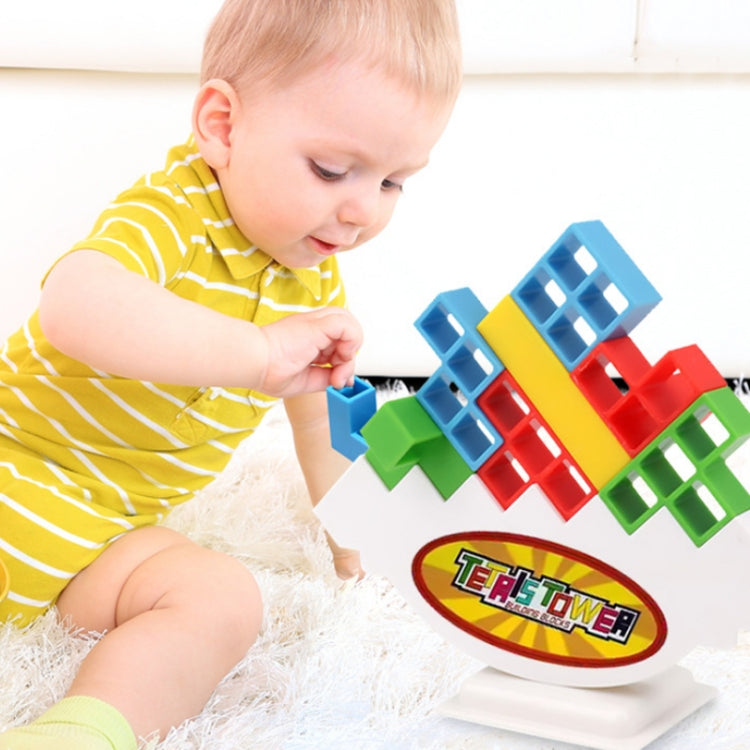 Young child playing with multicolor balance stack building blocks on a white stand