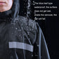 Black raincoat chest close-up with reflective band and water droplets on fabric.