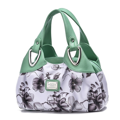 Green-handled soft leather handbag with white floral print and metal D-ring accents