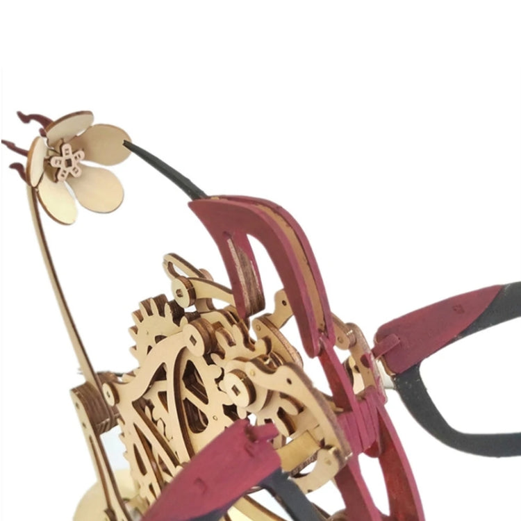 Close-up of 3D wooden hummingbird puzzle, tan gears with maroon wing frame