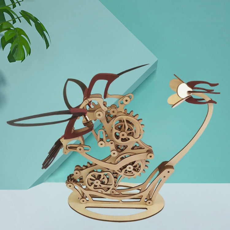 3D wooden mechanical hummingbird puzzle with black tail fins on tan base