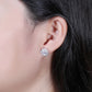 Silver flower stud earrings worn on ear, round center with petal stones