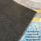 Non-slip rug backing with black dotted pattern and tan edge trim