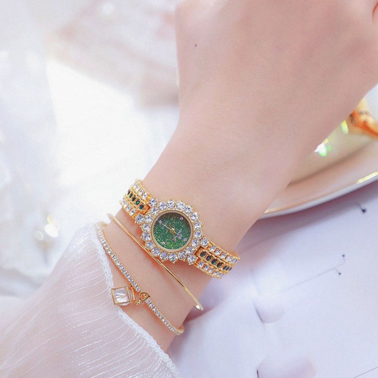 Women’s rhinestone watch on wrist with dark green dial and gold-tone chain band