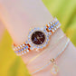Women’s sparkling chain watch with dark brown dial, gold-tone frame, blue accents