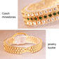 Gold-tone rhinestone watch bracelet with buckle closure and green stone detailing