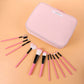 Pink zippered cosmetic pouch with makeup brushes laid out beside it