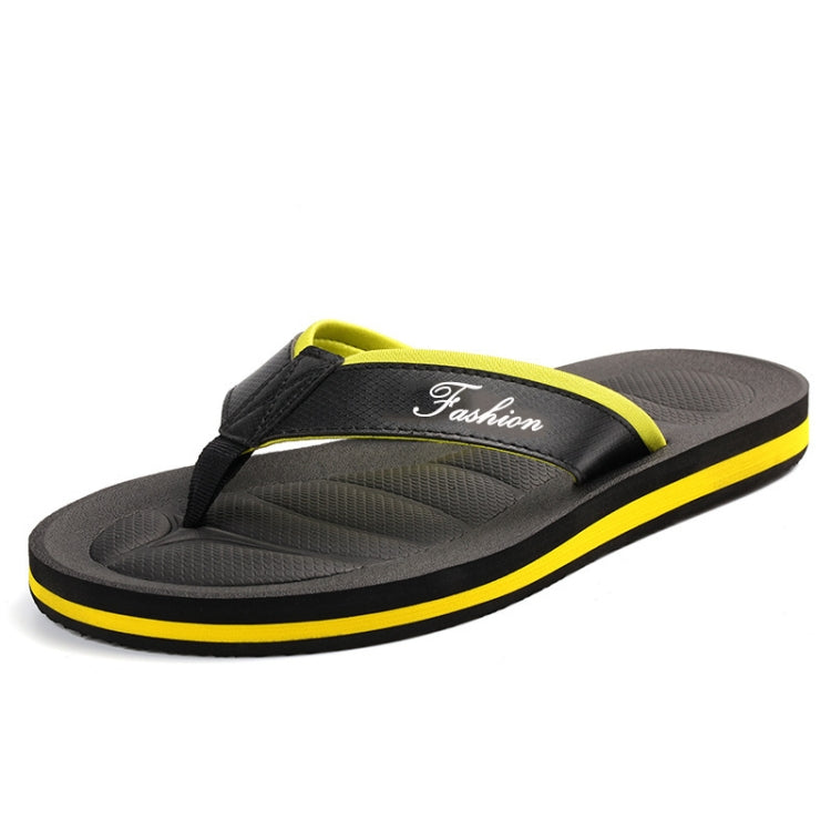 Men's black flip flops with yellow trim, strap with "Fashion" text, textured tread sole