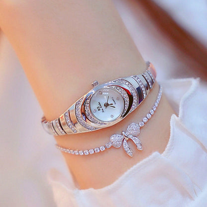 Silver oval ladies watch with rhinestone bezel and link bracelet, worn with charm detail