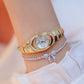 Gold oval ladies watch with rhinestone bezel and link bracelet, worn on the wrist