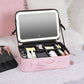 Pink makeup bag with built-in LED lamp, open organizer layout for cosmetics and bottles