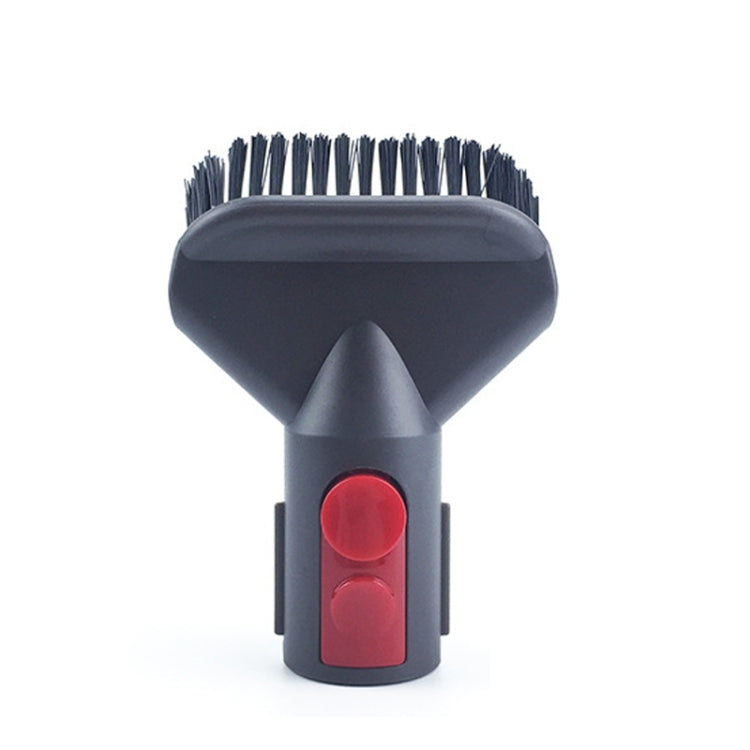 Small vacuum brush head with dark bristles and red control button.