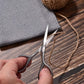 Hand using beard scissors for trimming, pointed blades and finger loops, silver metal