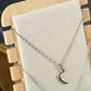 Beige necklace stand close-up with silver necklace chains and moon charm