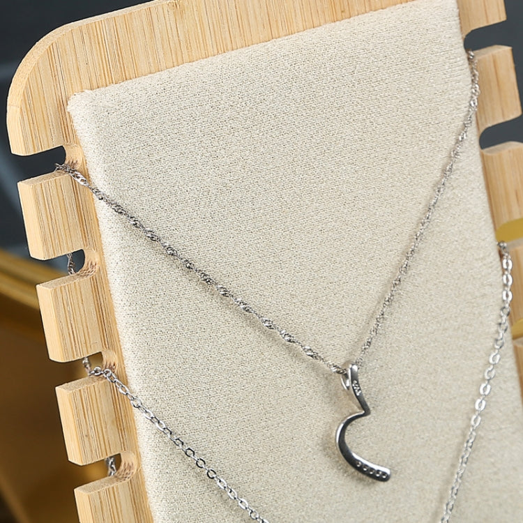 Beige necklace stand close-up with silver necklace chains and moon charm
