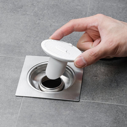 White magnetic suction floor drain cover with deodorizing vent, held by hand
