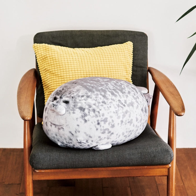 Speckled gray seal plush pillow on dark fabric cushion