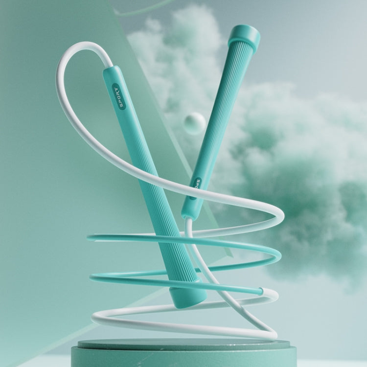 Kids skipping rope with green handles and white cord, coiled on stand.
