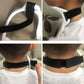 White neck brace with perforated black strap and center buckle adjustment