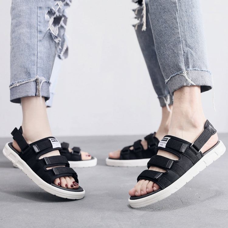 Men’s black sandals with thick sole and adjustable straps worn with rolled jeans