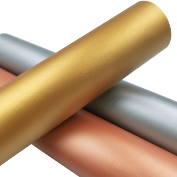 Matte metallic vinyl rolls stacked at an angle in gold, silver, and copper