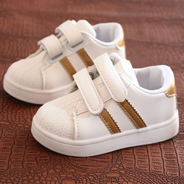 Children's white sneakers with gold side stripes and two-strap Velcro closures