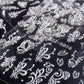 3D carved nail art sticker close-up with white leaf, bow, and scroll motifs on black