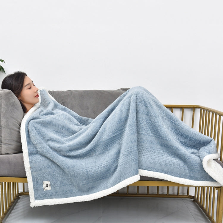 Misty blue flannel shawl blanket with white fleece trim laid over couch armrest