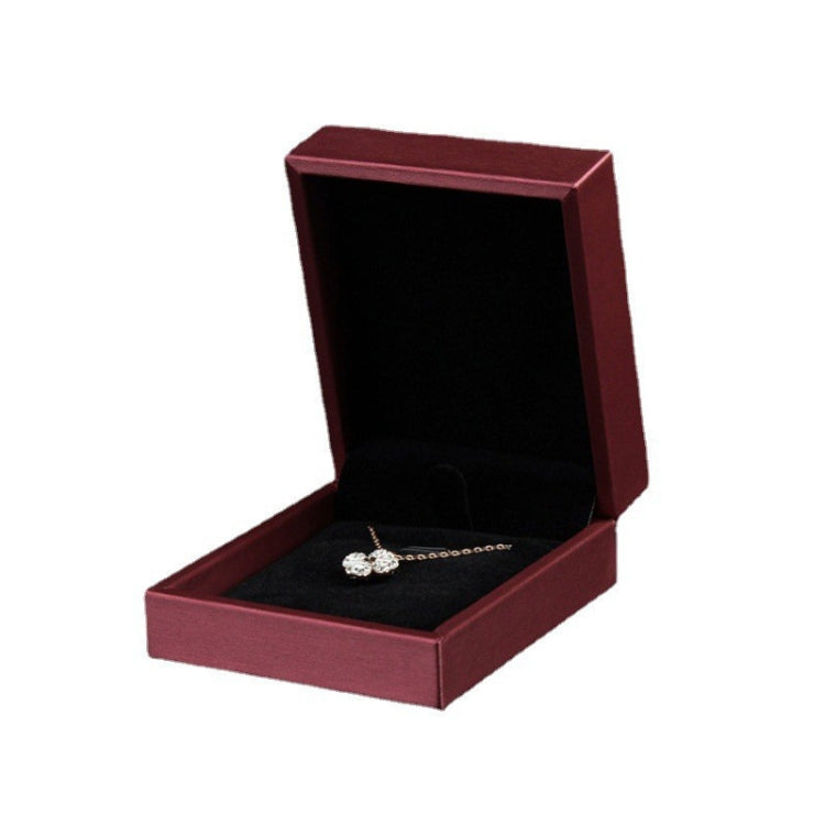 Wine red PU leather jewelry box with open lid and gold-toned necklace on black insert