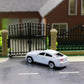 White small model car parked on a driveway scene with fence backdrop