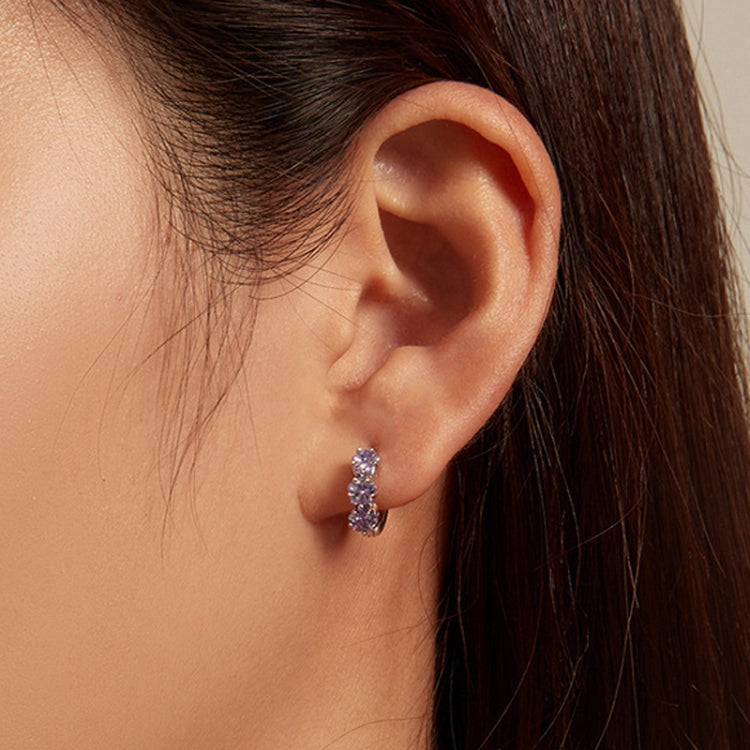 Purple zirconia three-stone hoop earrings worn on ear, silver