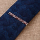 Men's tie with dark blue leaf pattern and rectangular tie clip with red scroll detail