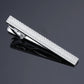 Textured silver tie clip with diamond pattern and polished metal clasp, hinged design.