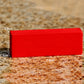 Red rectangular wooden game block piece with visible size markings