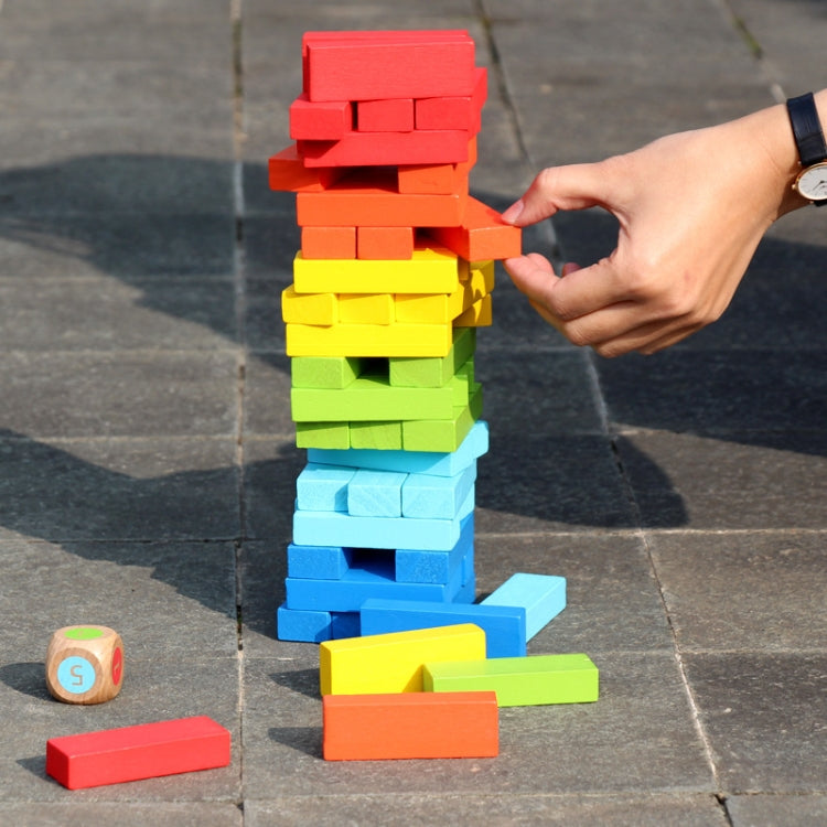Hand placing a colorful wooden block into a tall stacking game tower