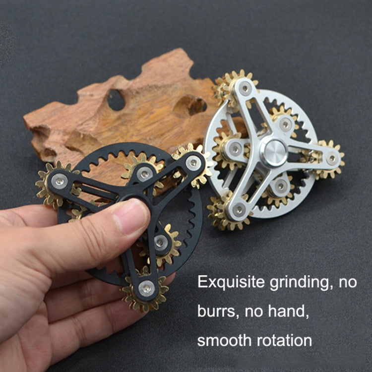 Four-gear fidget spinners held in hand: one black and one silver with gold gears.