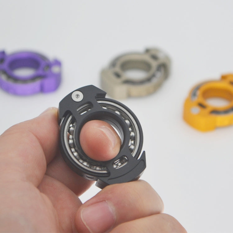 Black fingertip gyroscope held in a hand, showing the internal bearing ring