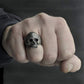 Skull ring on a hand, silver-tone with engraved teeth and hollow eye sockets
