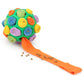 Green plush dog sniffing ball with orange treat-feeding strip and scattered kibble