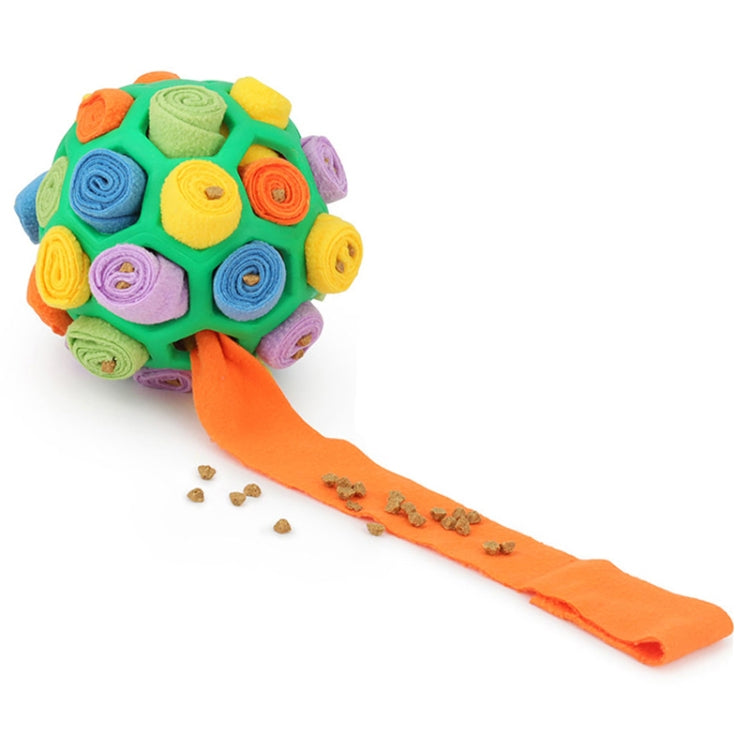 Green plush dog sniffing ball with orange treat-feeding strip and scattered kibble
