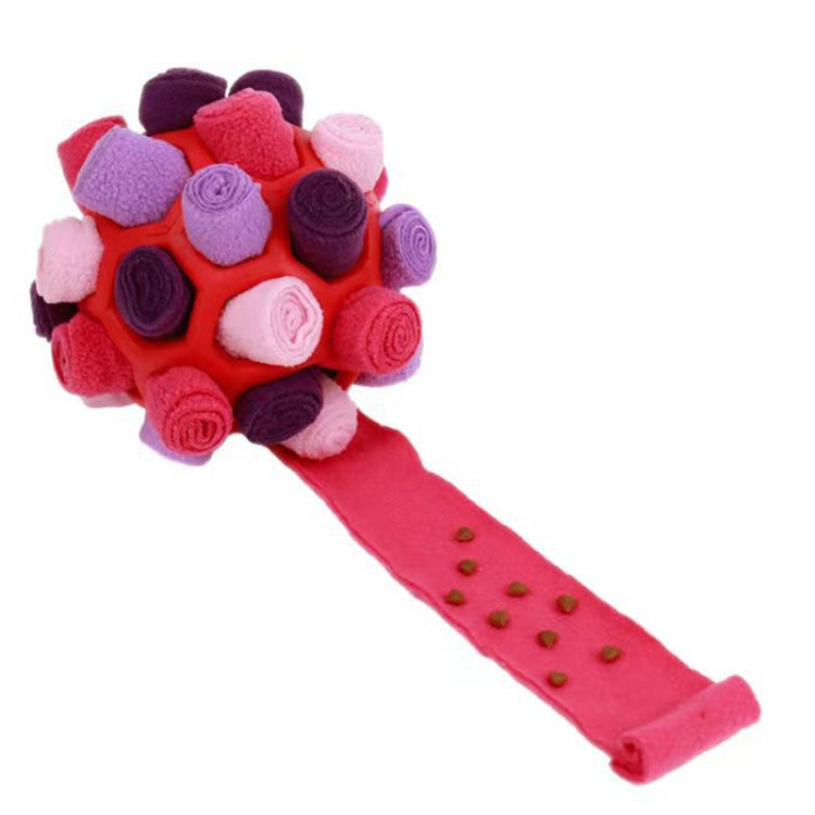 Red and pink plush dog sniffing ball with pink treat-feeding strip and scattered kibble