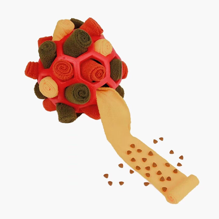 Red plush dog sniffing ball with beige treat-feeding strip and scattered kibble