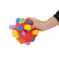Rainbow plush dog sniffing ball toy held in hand, textured fabric swirl details
