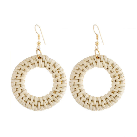 Handmade woven circular hoop earrings with gold-tone ear hooks, natural beige fiber.