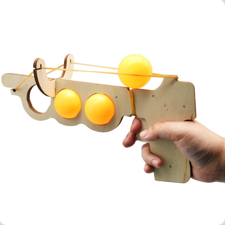 Wooden elastic table tennis launcher toy held in hand with three yellow balls