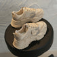 Beige lace-up sports shoes with thick cushioned soles and breathable mesh upper